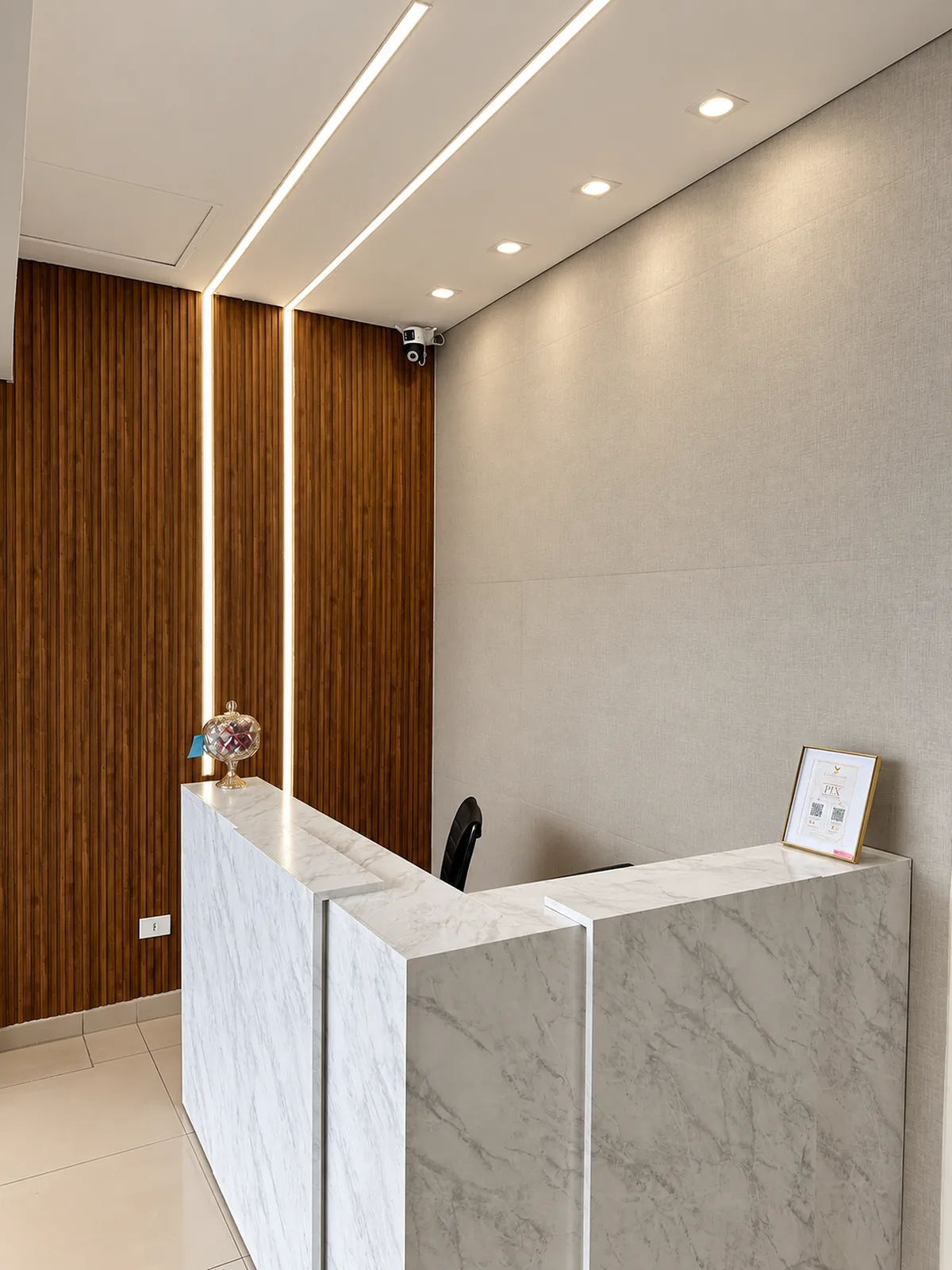 Recepção da Clínica Landim, com balcão de mármore e painel de madeira
