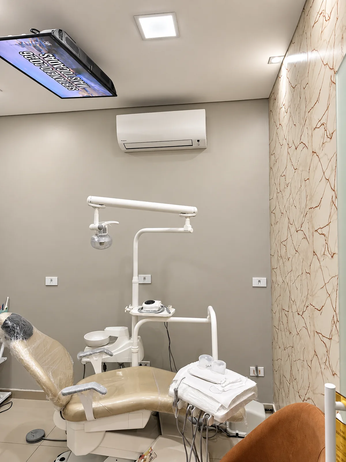 Consultório odontológico com televisão no teto para o paciente