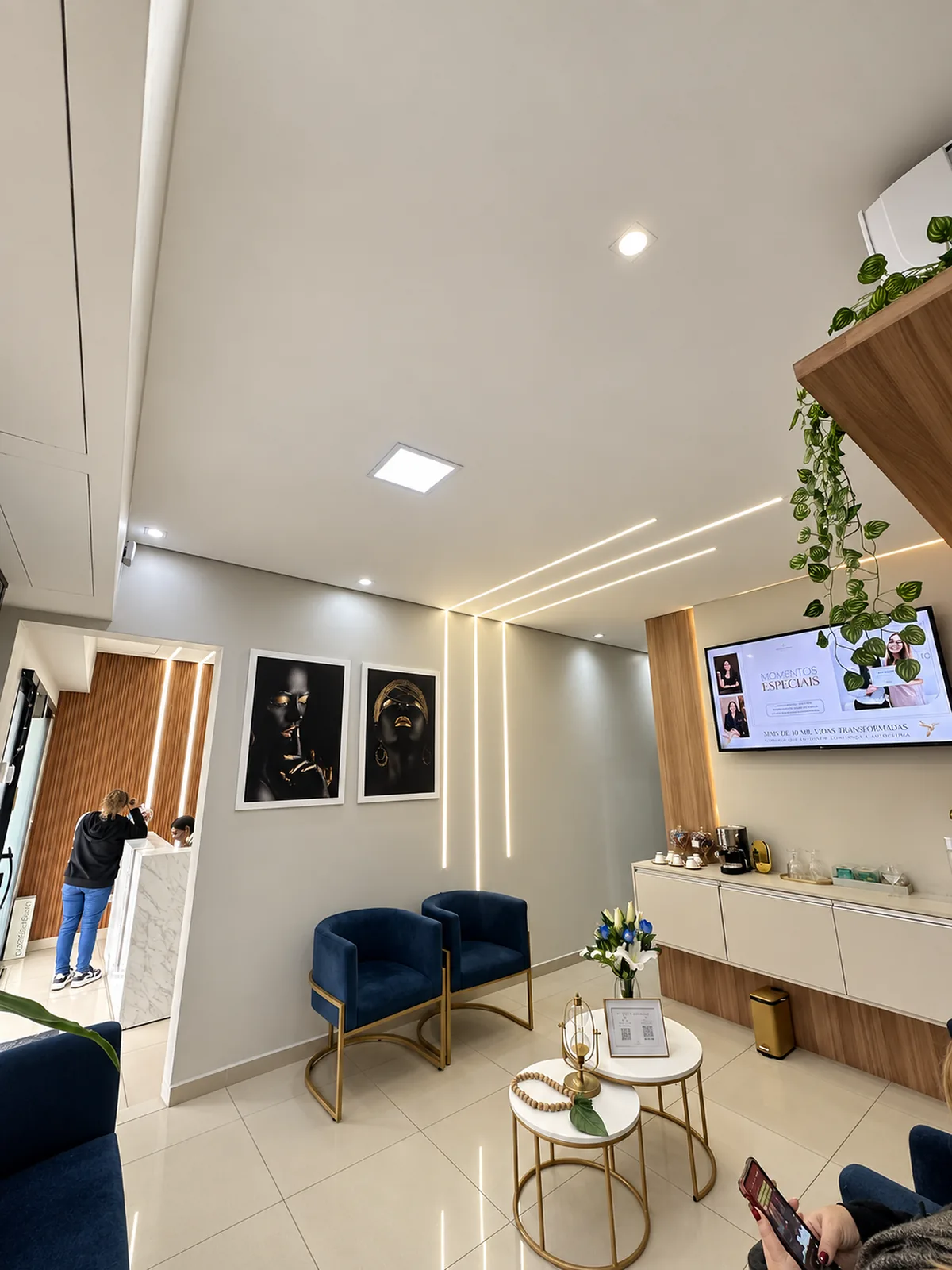 Sala de espera da Clínica Landim, com poltronas azuis, televisão e quadros