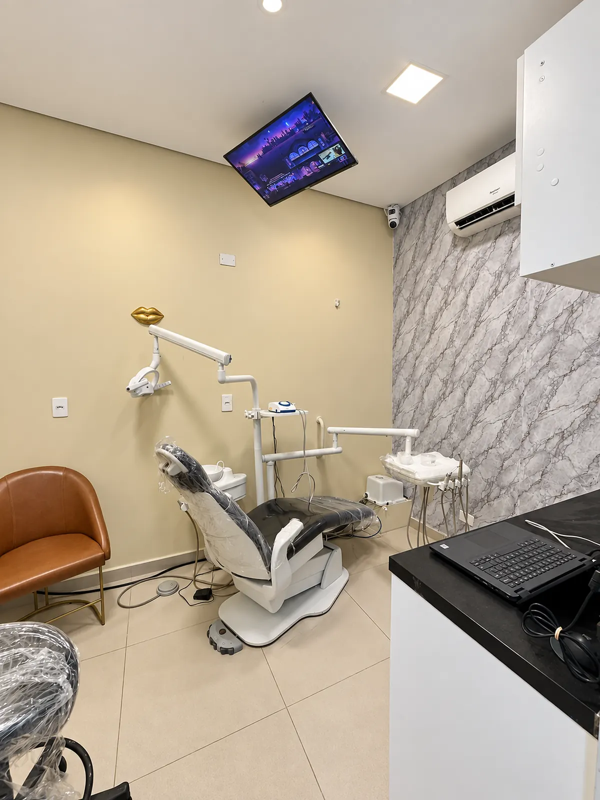 Consultório odontológico com cadeira, refletor e parede de mármore